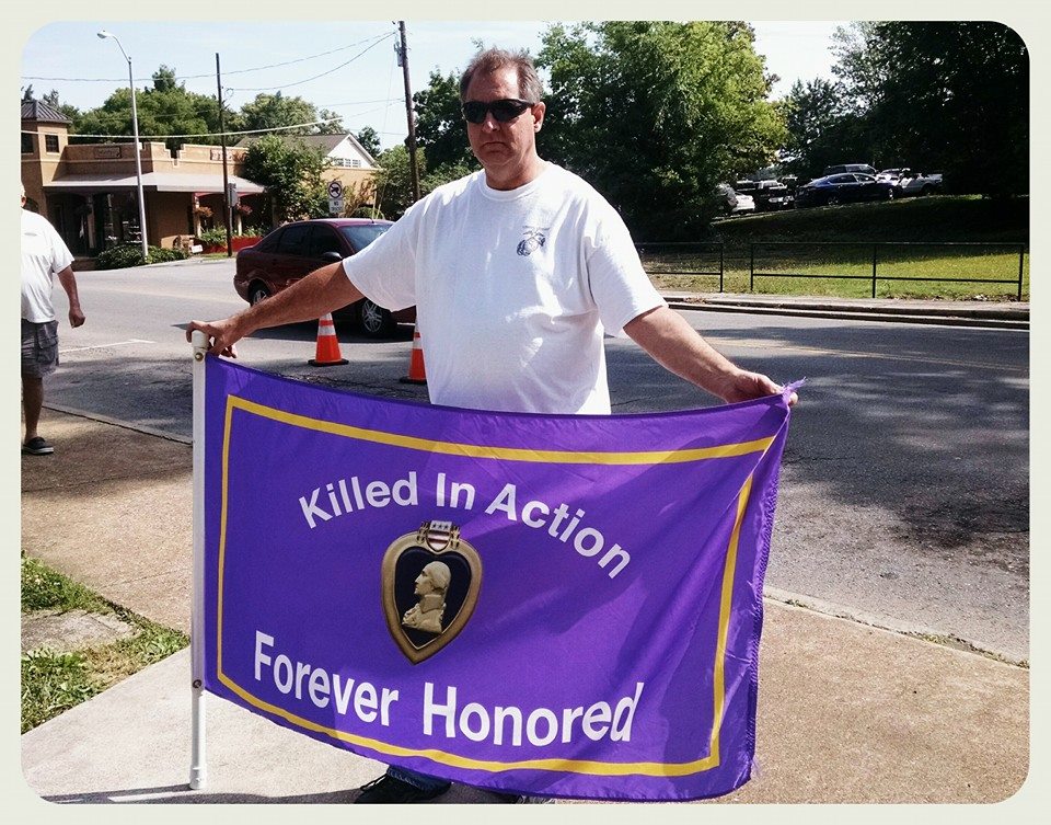 Man holding Purple Heart flag out