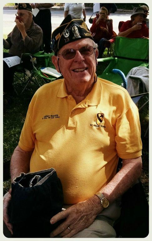 Man in yellow shirt, sitting and smiling, wearing hat