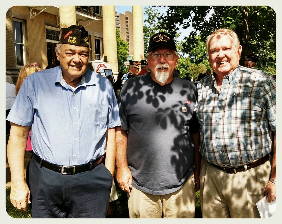 Three men standing in shade smiling