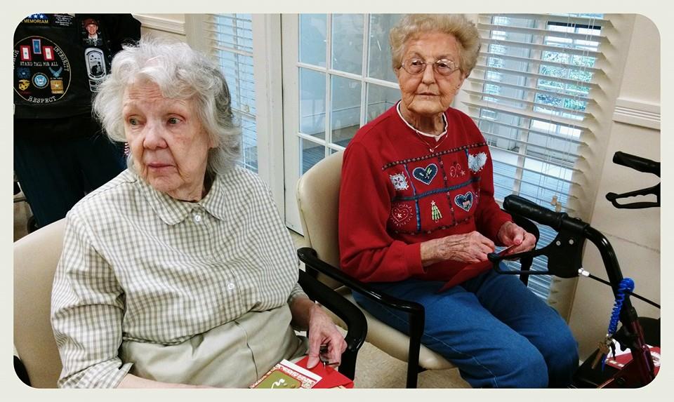 Two sitting woman veterans look past the camera while opening cards
