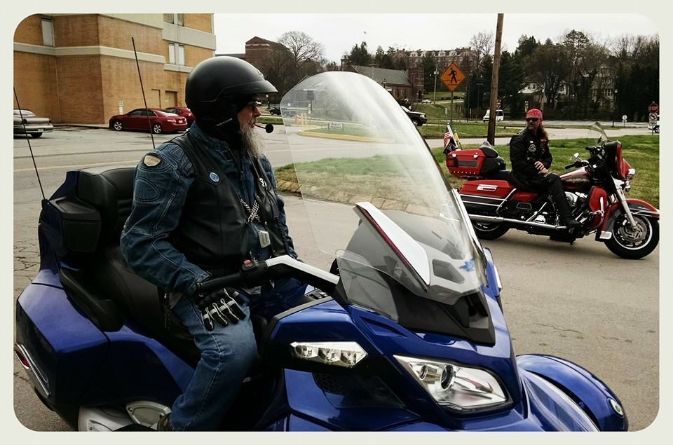 Man in jeans sits astride blue motorcycle