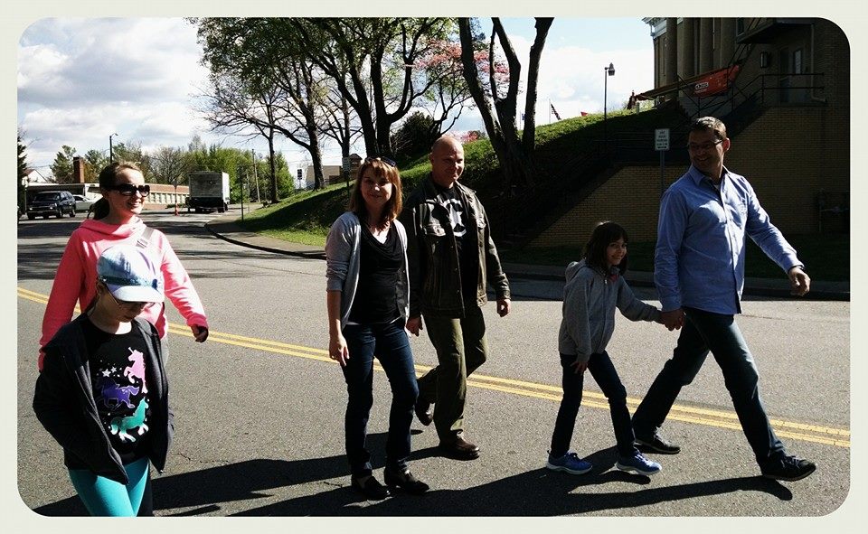 Two young girls walk with four adults on street