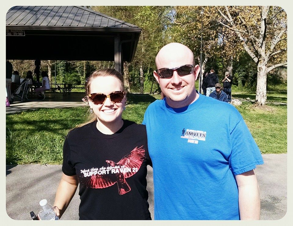 Man and woman stand with sunglasses on, smiling into camera