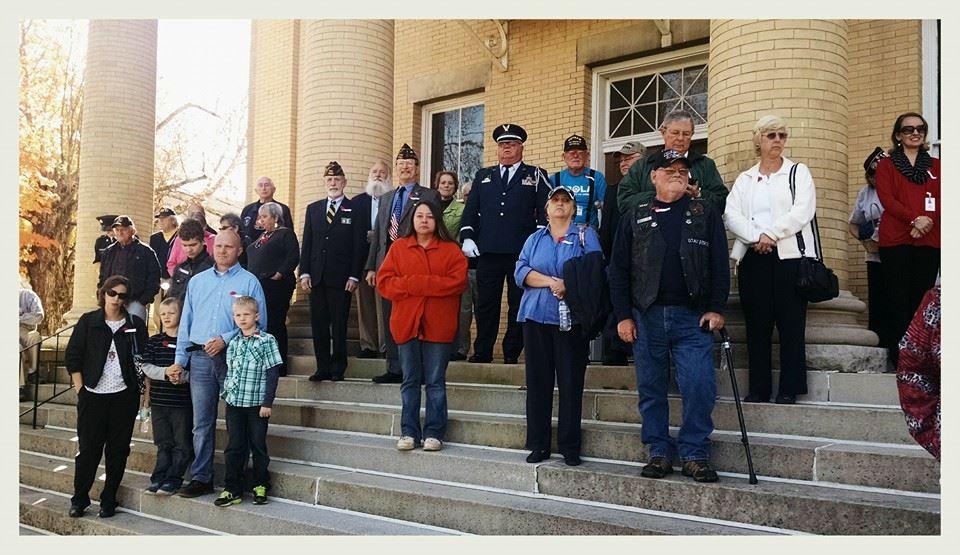 Crowd watches something behind cameraman from Court house steps