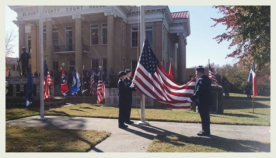 Cadets hold the American flag as it is raised on the pole in frotn of the Court house