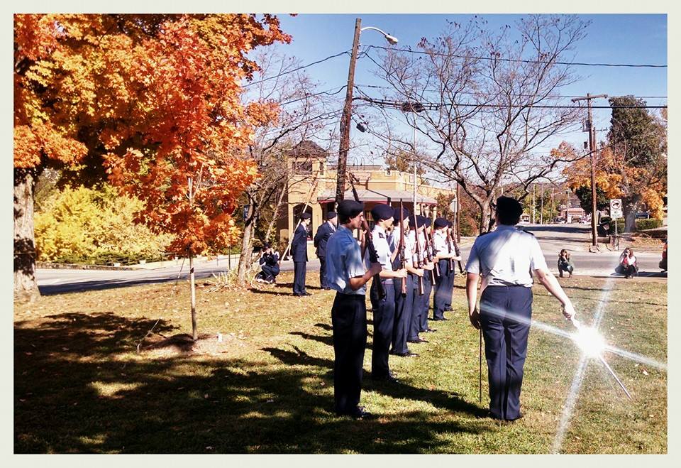 Line of cadets with firearms in front of their chests, leader with sabre