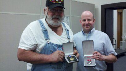 Nathan Weinbaum stands beside man in overrals, both display medals