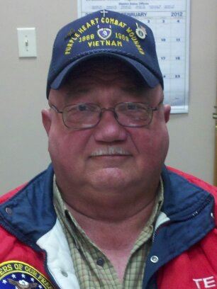 Up close image of man with glasses wearing Purple Heart Combat Wounded hat
