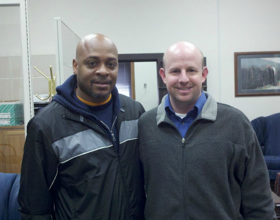 Nathan Wienbaum side hugs visitor in black and grey jacket
