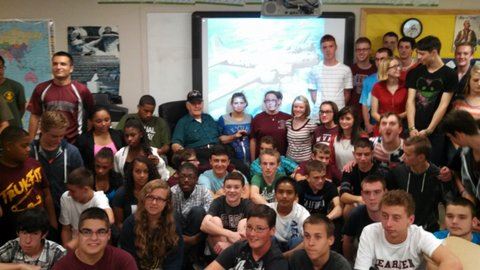 Image od classroom with veteran sitting in cahri surrounded by class of teeneagers