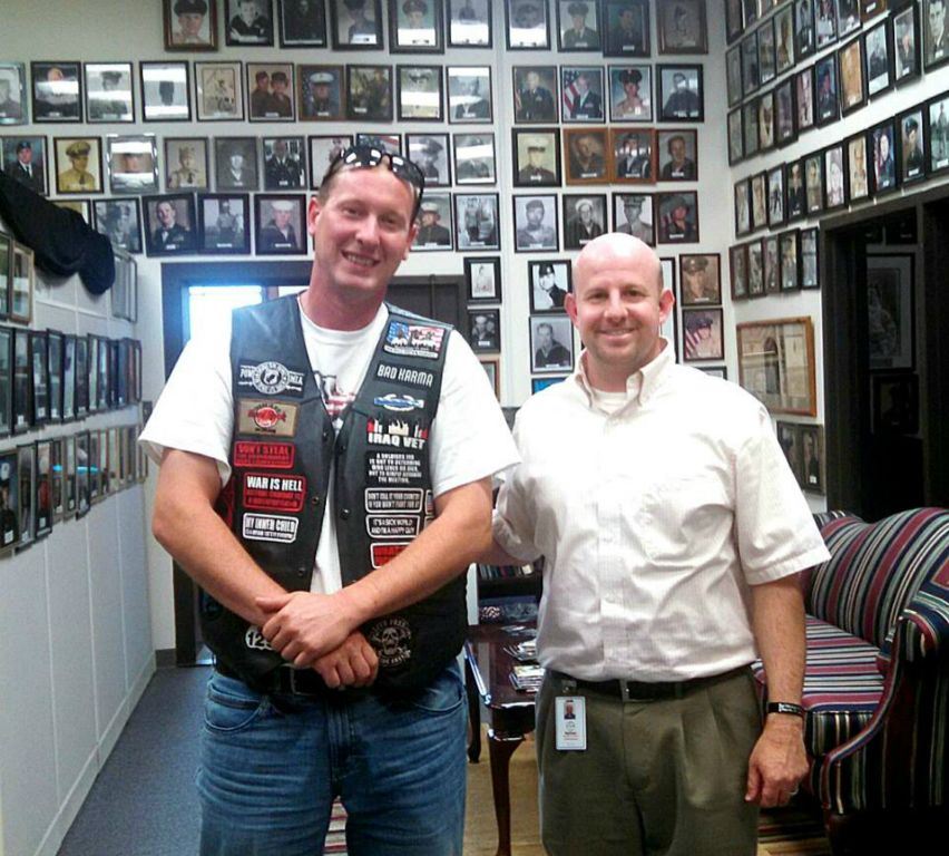 Nathan Weinbaum stands with man in white shirt with black leather vest with patches, both men looking into the camera smiling