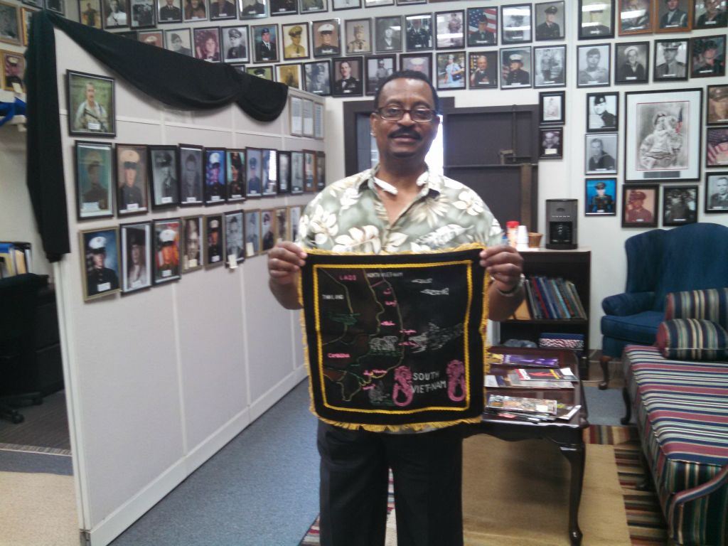 Man holds square map flag of South Vietnam, standing in Veterans Affairs office