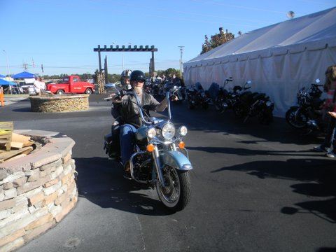 Motorcyclist rides blue bike in lot in front of white tent