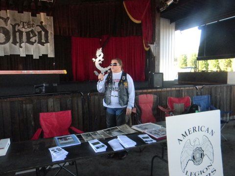 Woman in black leather vest stands behind table with brochures and pamphlets