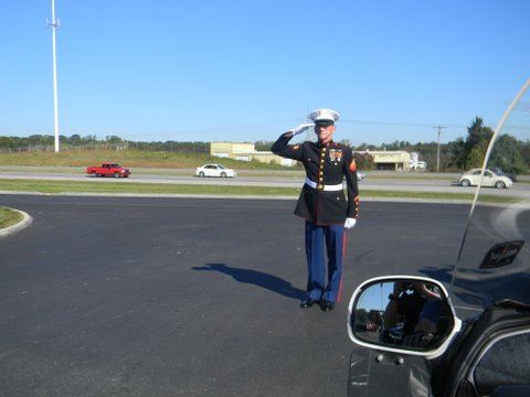 Marine in dress uniform salutes vehicle from road