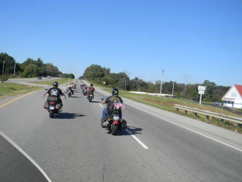 Image taken from motorcycle of motorcycles in front on road with grass on sides