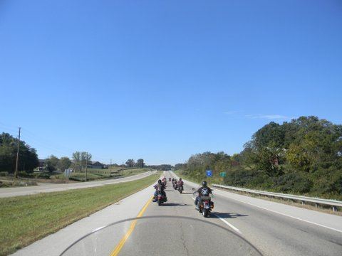 Image of motorcycles on road with trees on sides