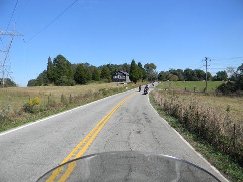 Vista from motorcycle of street, powerlines, and farmlands, and barn