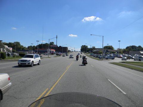 Picture taken from motorcycle of street with cars and bikes