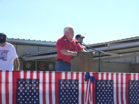 Man in red shirt speaking at podium