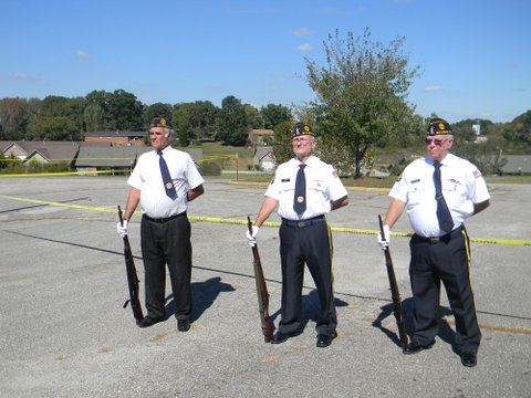 Three men in white shirts with black pants, holding rifles at ease
