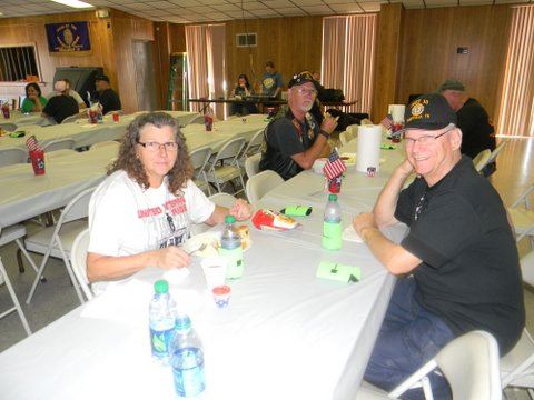 four veterans sit at banquet table, looking into camera smiling